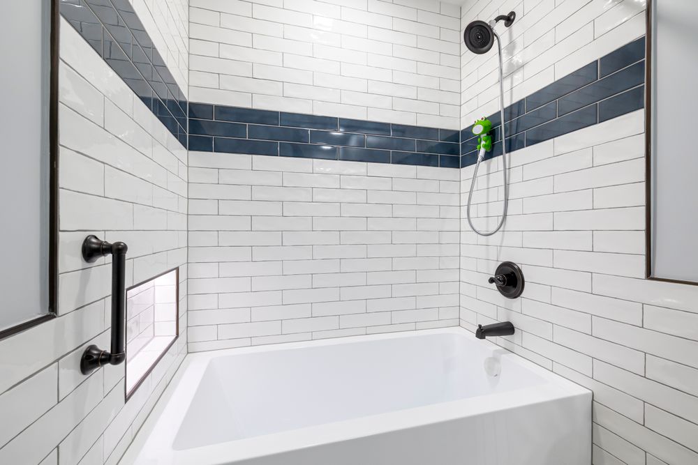 A remodeled bathroom with white subway tile and a navy accent band