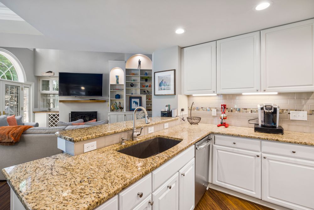 A renovated kitchen with white cabinets and granite counters