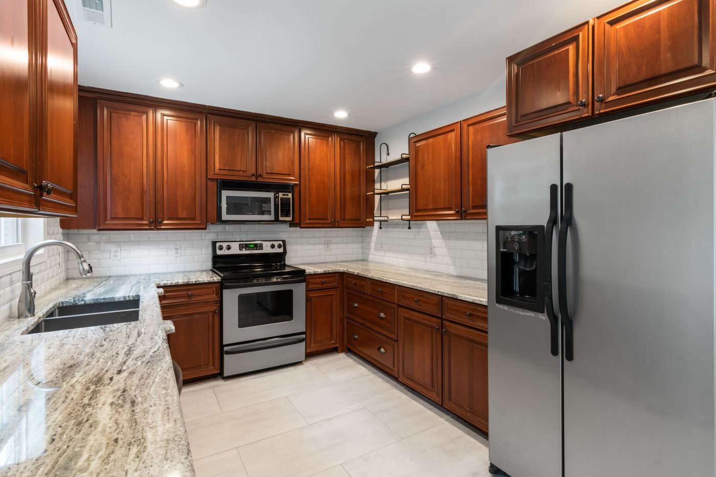 A remodeled kitchen with wood cabinets, granite counters and stainless appliances