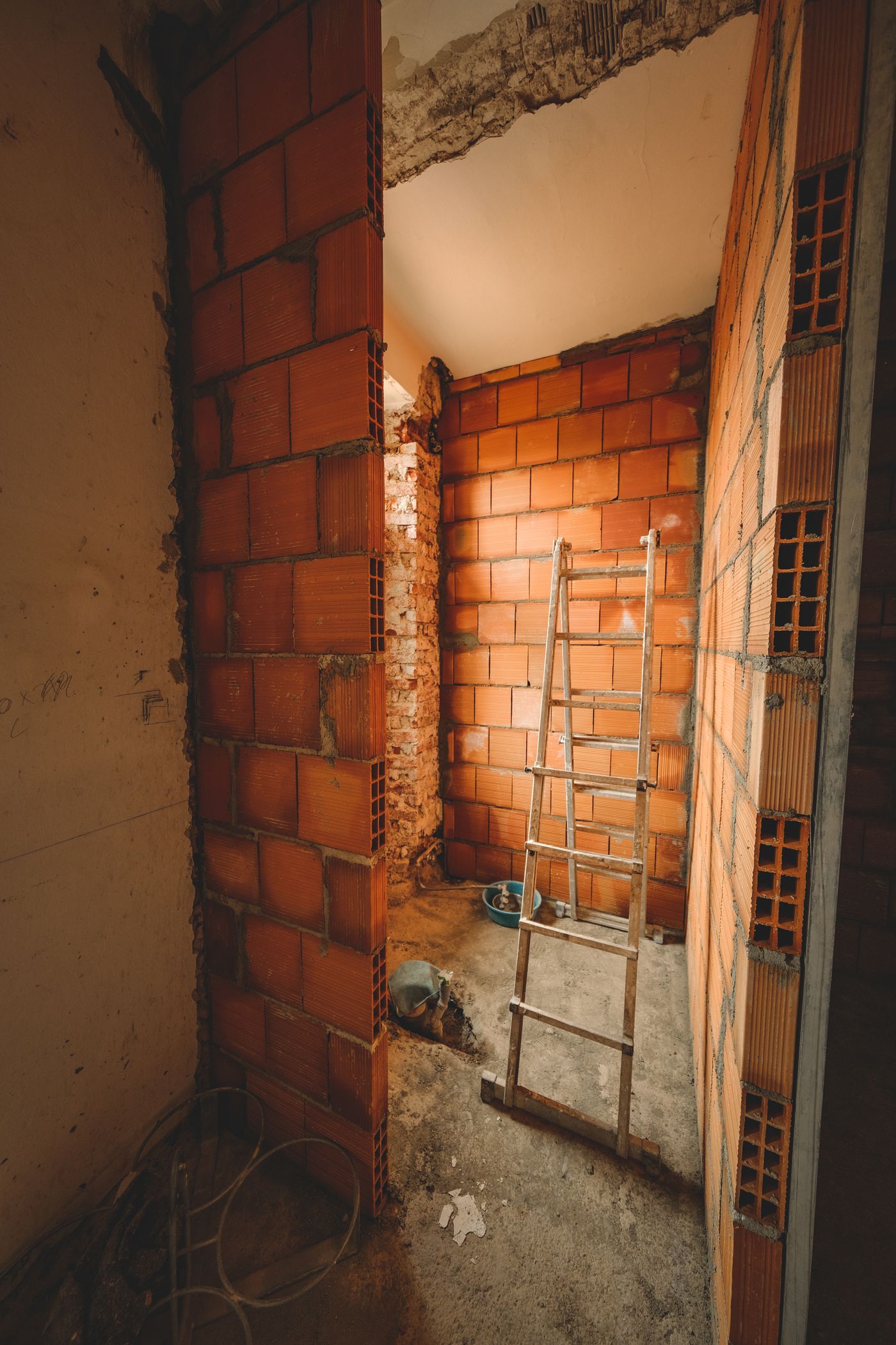 A room stripped back to bare masonry mid-renovation with a work ladder in place