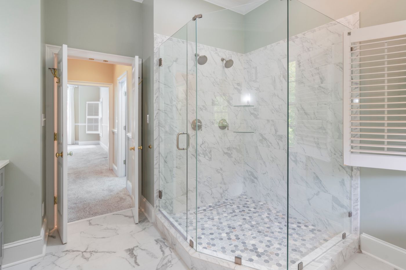 A tiled bathroom wall and tub surround finished in marble-look stone